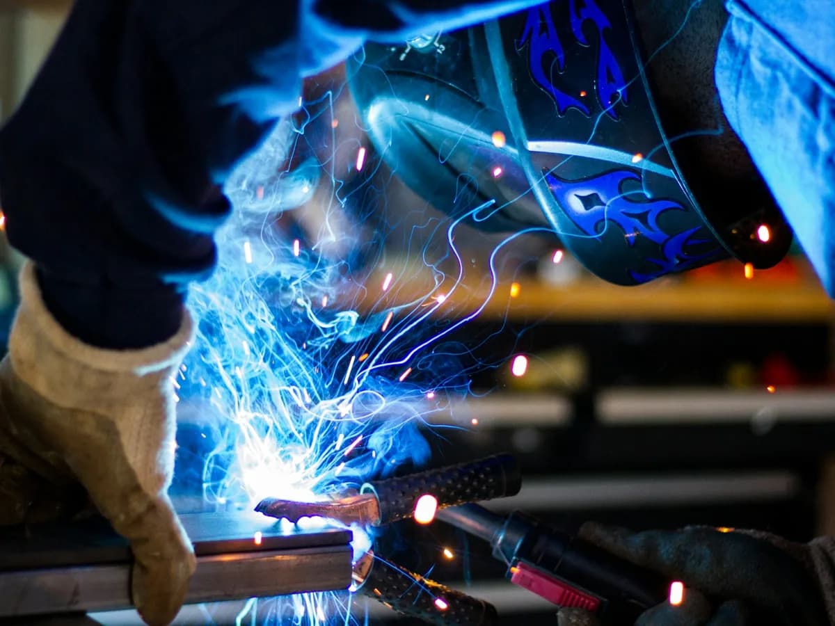 A welder working on a steel assembly in an industrial shop