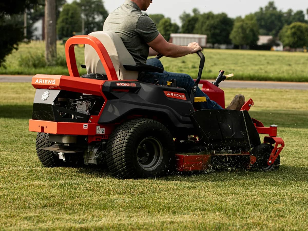 A crew member mowing a large lawn on a commercial mower